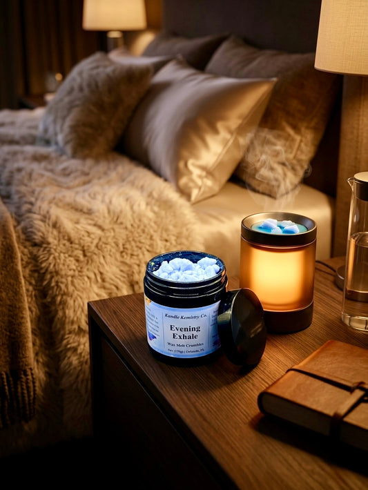 Jar of 'Evening Exhale' wax melts on a bedside table with a lit candle and notebook in a cozy bedroom setting.