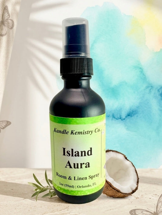 Bottle of Island Aura room and linen spray with a coconut and leaves on a light background
