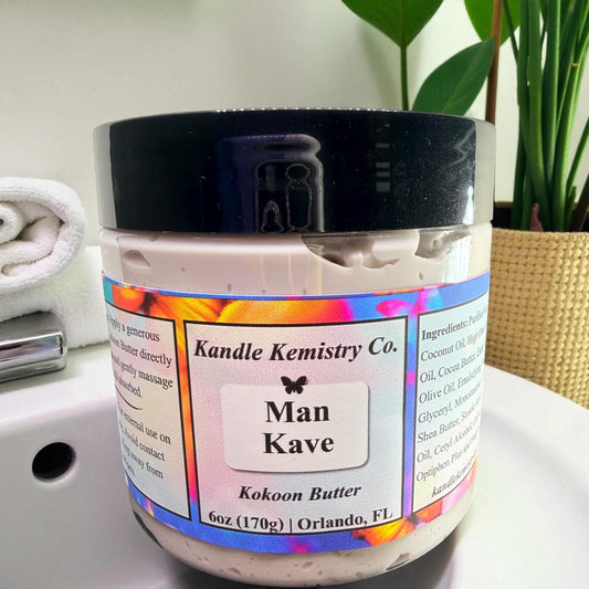 Jar of Man Kave Kokoon Butter by Kandle Kemistry Co. on a bathroom counter with a plant in the background.