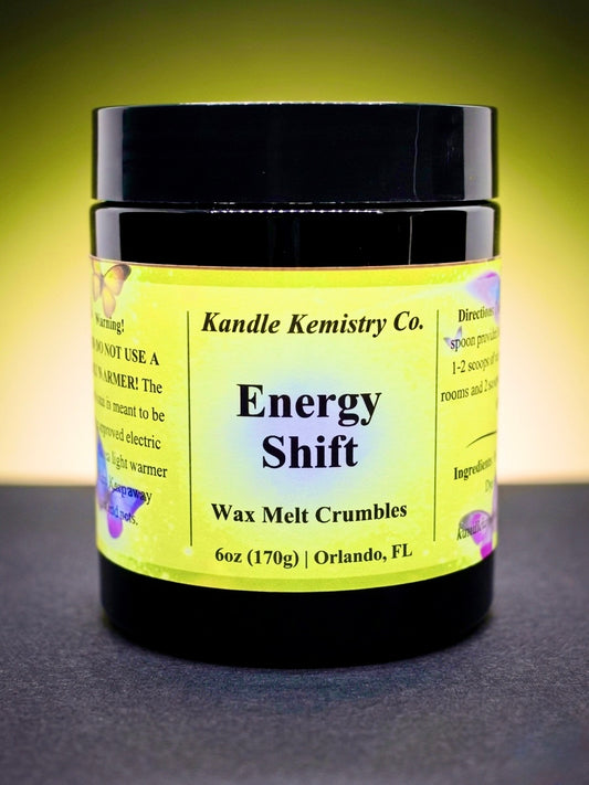 Jar of 'Energy Shift' wax melt crumbles from Kandle Kemistry Co. on a dark surface with a yellow background.