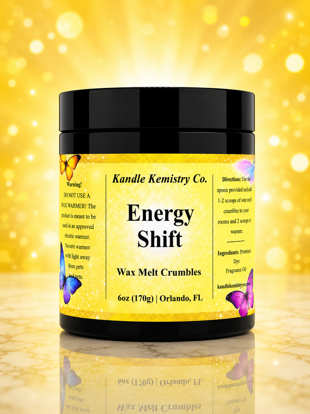 A jar of Kandle Kemistry Co. Energy Shift Wax Melt Crumbles, featuring a black lid and a bright yellow label with butterfly illustrations, set against a sparkling gold background.