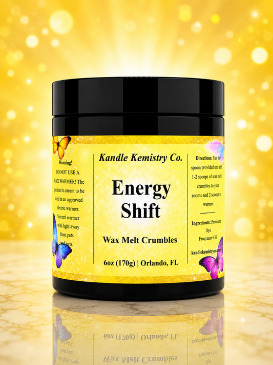 A jar of Kandle Kemistry Co. Energy Shift Wax Melt Crumbles, featuring a black lid and a bright yellow label with butterfly illustrations, set against a sparkling gold background.