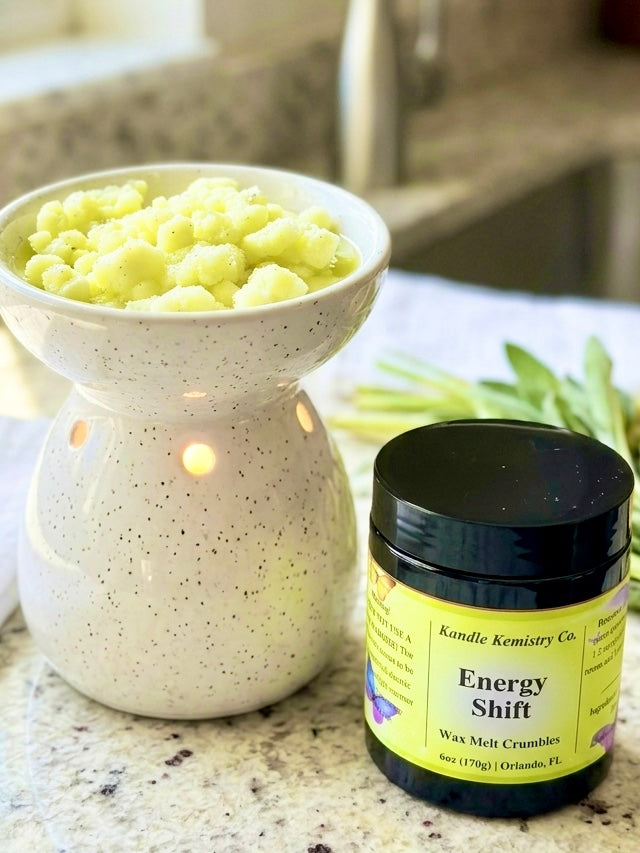 Jar of 'Energy Shift' wax melt crumbles next to a wax warmer on a countertop.