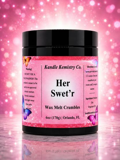 A black plastic jar of Kandle Kemistry Co. 'Her Swet'r' Wax Melt Crumbles, featuring a pink glittery label with purple butterflies, set against a pink bokeh background.