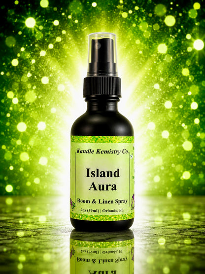 A bottle of Island Aura Room & Linen Spray by Kandle Kemistry Co. The product is in a black glass bottle with a black spray pump and a light green label, set against a vibrant green bokeh background.