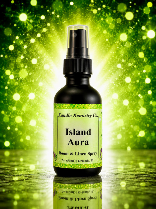 A bottle of Island Aura Room & Linen Spray by Kandle Kemistry Co. The product is in a black glass bottle with a black spray pump and a light green label, set against a vibrant green bokeh background.