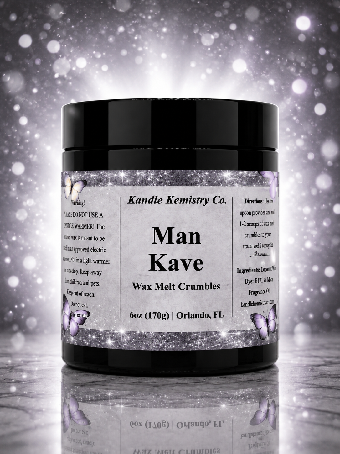 A black plastic jar of Kandle Kemistry Co. Man Kave Wax Melt Crumbles, featuring a white label with black text and butterfly illustrations, set against a sparkling silver and white background.