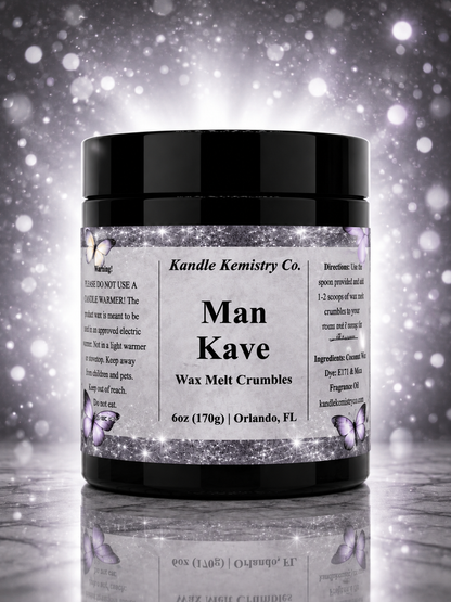 A black plastic jar of Kandle Kemistry Co. Man Kave Wax Melt Crumbles, featuring a white label with black text and butterfly illustrations, set against a sparkling silver and white background.