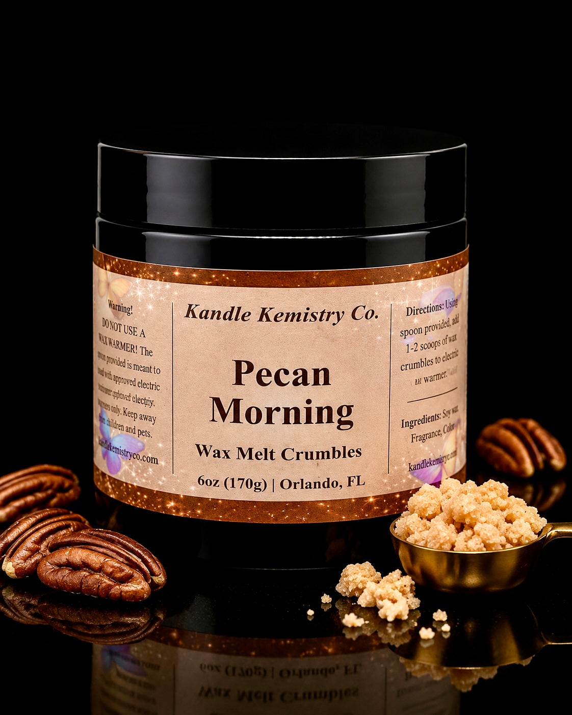 A jar of Kandle Kemistry Co. Pecan Morning Wax Melt Crumbles, styled with whole pecans and a gold scoop of the crumbles on a reflective black surface.