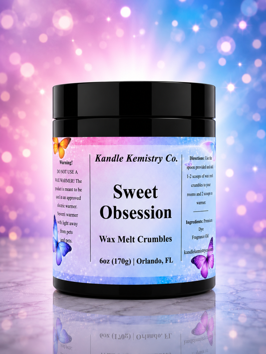 A black plastic jar of Kandle Kemistry Co. 'Sweet Obsession' wax melt crumbles, featuring a white label with black text and butterfly illustrations, set against a colorful purple and blue bokeh background.
